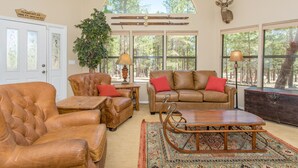A spacious living room with leather furniture, a large window, and a deer head mounted on the wall.