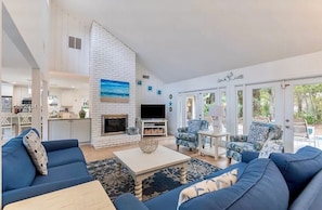 Un salón amplio con chimenea, sofás azules y televisión.