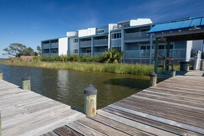 A waterfront property with a wooden dock leading to a building with multiple balconies.