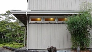 A two-story building with a stone foundation and a flat roof. - Gorgeous! The Waterfall Retreat At Reed's Island (Hilo)