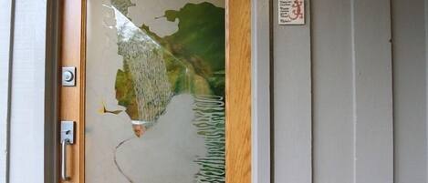 A wooden door with a glass panel featuring a landscape design.