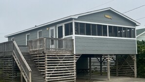 A two-story building with a wooden deck and stairs leading to the entrance.