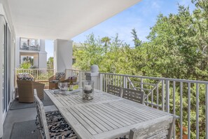 A balcony with a wooden table, wicker chairs, and a glass candle holder.