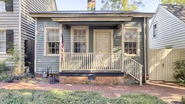 A two-story house with a front porch, a chimney, and a small front yard.