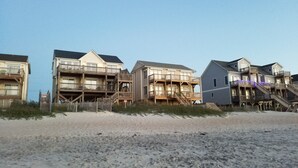Ein Strandgrundstück mit mehreren Gebäuden, darunter ein großes Haus mit Balkon und ein kleineres Gebäude mit Veranda.