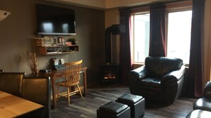 Ein Wohnzimmer mit Kamin, Fernseher, Esstisch und einer Couch.