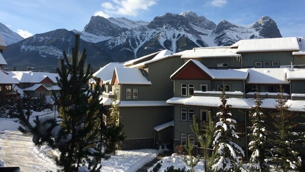 Ein mit Schnee bedecktes Gebäude vor einer Bergkulisse.