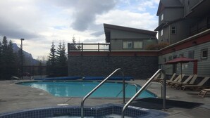 Ein Swimmingpool mit Whirlpool, Liegestühlen und einem Steingebäude im Hintergrund.