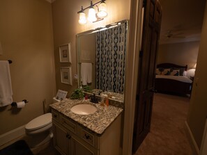A bathroom with a sink, toilet, and mirror. There is a towel rack and a sign on the wall. - Gorgeous lakefront home with infinity pool, pickleball court, stunning lake view (Dawsonville)