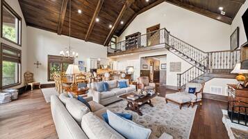 A spacious living room with a high ceiling, a staircase, and a dining area.