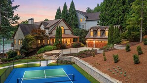 Una propiedad residencial con cancha de tenis, varias casas y un jardín ajardinado.