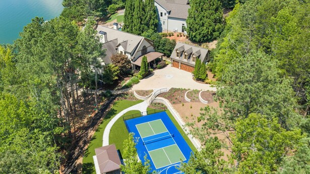 Un quartier résidentiel doté d’un court de tennis, d’un quai pour bateaux et d’une grande maison entourée d’arbres.