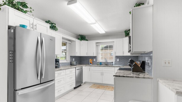 A modern kitchen with white cabinets, stainless steel appliances, and a marble countertop. - Waterfront in Crystal River! Scalloper's Heaven, Boaters Dream, see manatees (Crystal River)