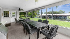 A covered patio with a table and chairs, large windows, and a view of a water body. - Waterfront in Crystal River! Scalloper's Heaven, Boaters Dream, see manatees (Crystal River)