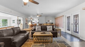 A spacious living room with a leather sofa, a wooden coffee table, and a ceiling fan. - Waterfront in Crystal River! Scalloper's Heaven, Boaters Dream, see manatees (Crystal River)