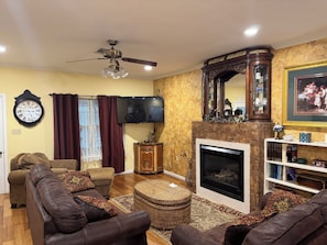 Relax in this inviting living room with a leather sofa, sideboard, flat-screen TV, and fireplace.