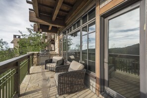 A covered outdoor patio with wicker furniture, a grill, and a view of the surrounding landscape. - New Ultra-Luxury Upper Deer Valley Ski in/Out Condominium..  (Park City)