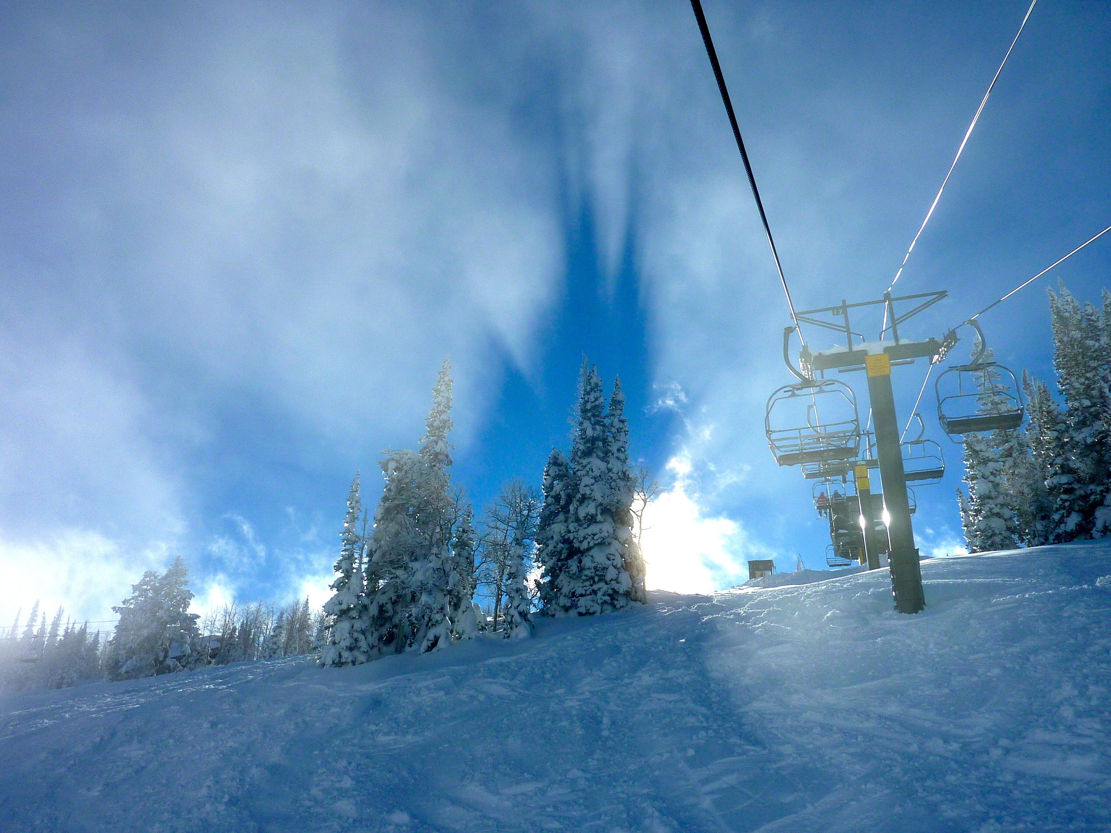 A ski lift with snow-covered trees in the background.