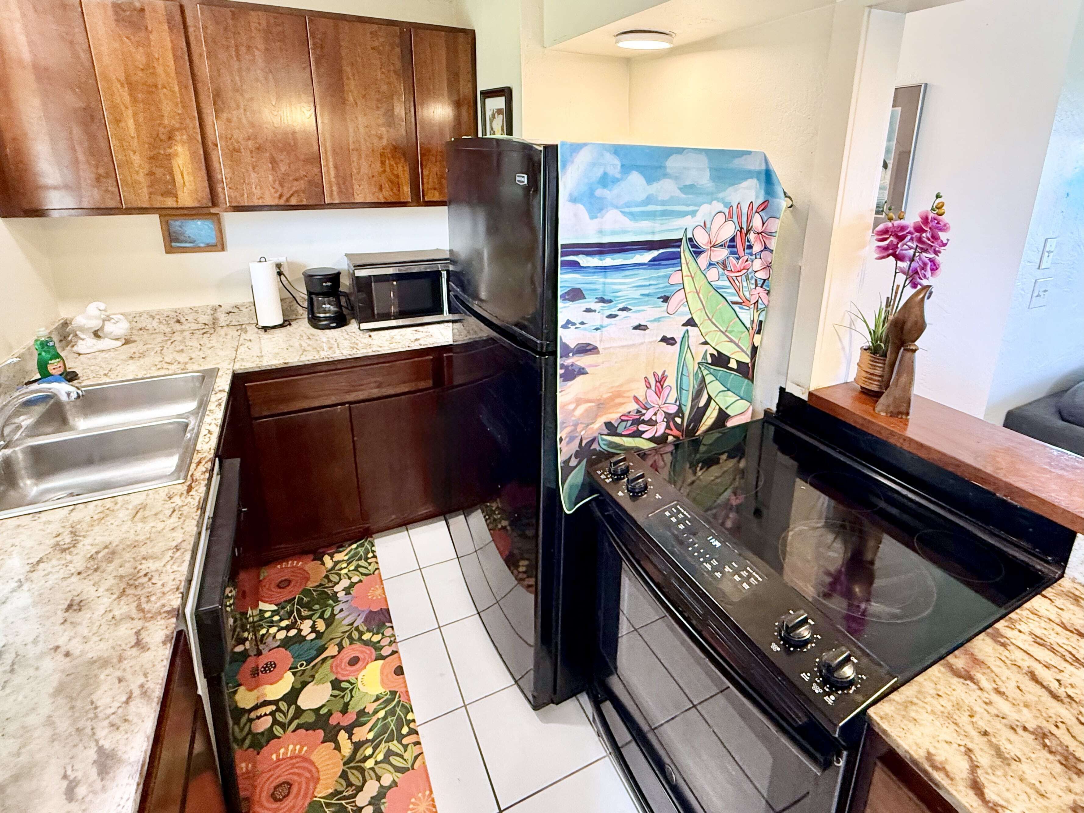 A kitchen with wooden cabinets, a stainless steel sink, a microwave, and a stove.