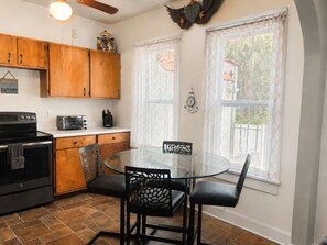 A kitchen with wooden cabinets, a stove, a toaster, and a glass dining table with chairs.