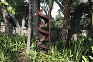 A metal spiral structure amidst greenery and trees.