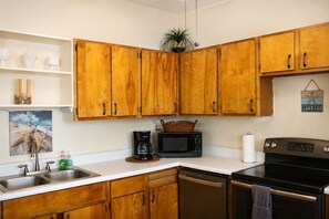 Una cocina con armarios de madera, cafetera, microondas, lavavajillas y estufa.