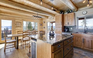 A spacious kitchen with wooden cabinets, a granite countertop, and a view of the mountains. - Top of the Mountain Log Home with BREATHTAKING VIEWS near Winter Park, Granby (Tabernash)