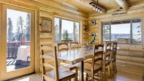 Een houten chalet met een eethoek, grote ramen en een bord waarop staat 'Koffie... Wijn'.