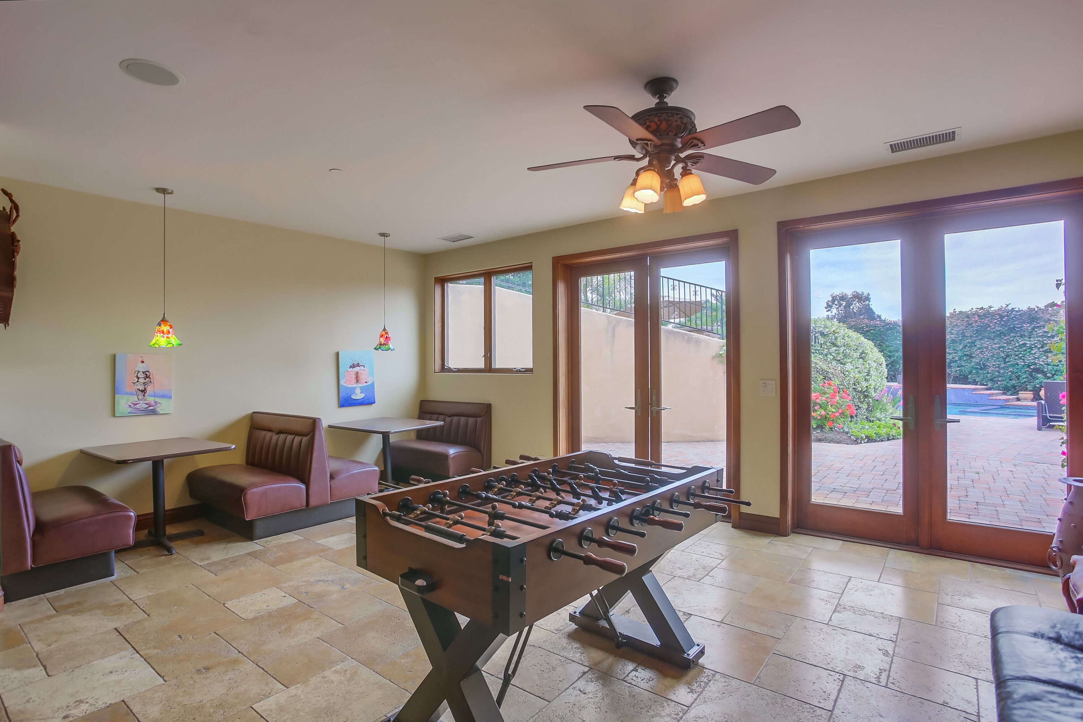 A spacious room with a foosball table, seating area, and large sliding glass doors leading to an outdoor patio.