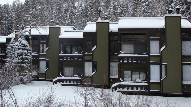 En rad stugor med balkonger, omgivna av snötäckta träd.