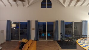 A spacious living area with a sofa, a poolside table, and a ceiling fan.