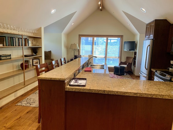 A modern kitchen with a central island, built-in appliances, and a dining area with a view of the city.