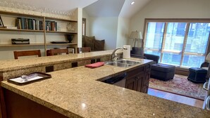 Uma cozinha com bancadas de granito, pia embutida e área de refeições com mesa e cadeiras.