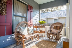 A porch with wicker furniture, a potted plant, and a wooden fence. - Charming Bungalow Located In The Heart Of Fredericksburg. 3 blocks from Main. (Fredericksburg)