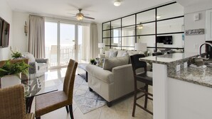 A modern living room with a sofa, chairs, a dining table, and a kitchen area.