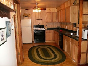 Enjoy cooking in this well-equipped kitchen with a stove, ceiling fan, and wooden floor.