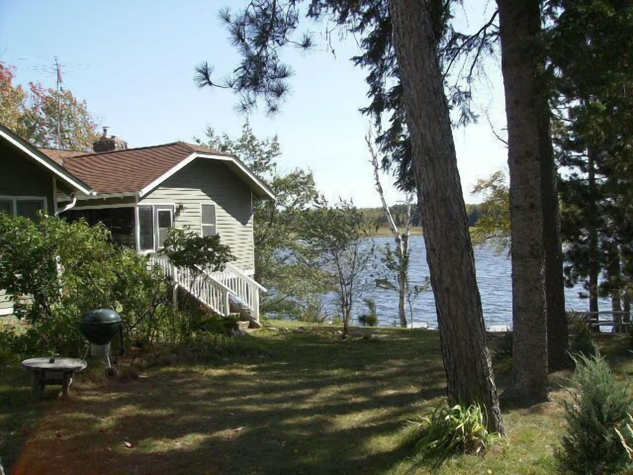 Une maison avec un porche, un barbecue et une vue sur un lac.