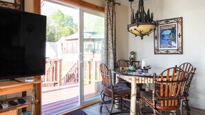 Un coin repas avec une table en bois, des chaises et un téléviseur posé sur un meuble.