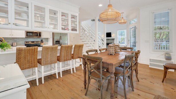 A spacious kitchen with white cabinetry, a wooden dining table, and wicker chairs. - Summer Wind: Poolside Retreat Near the Beach & Village (St. Simons Island)