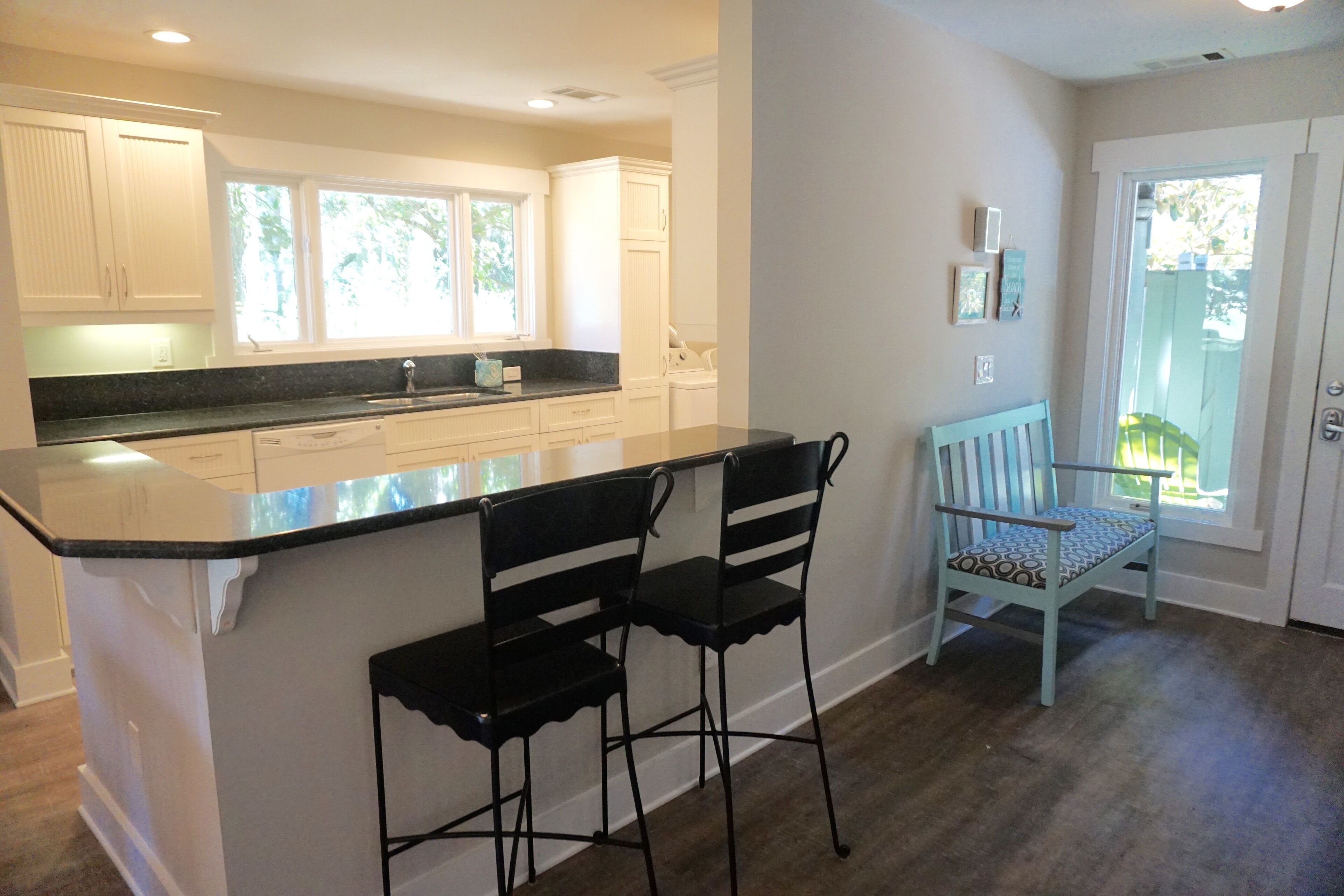 A kitchen with a large island, two bar stools, and a window with a view.