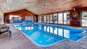Una piscina interior con techo de madera y amplias ventanas.