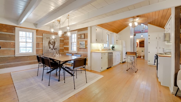 Una cocina amplia con pisos de madera, armarios blancos y un comedor con mesa y sillas.