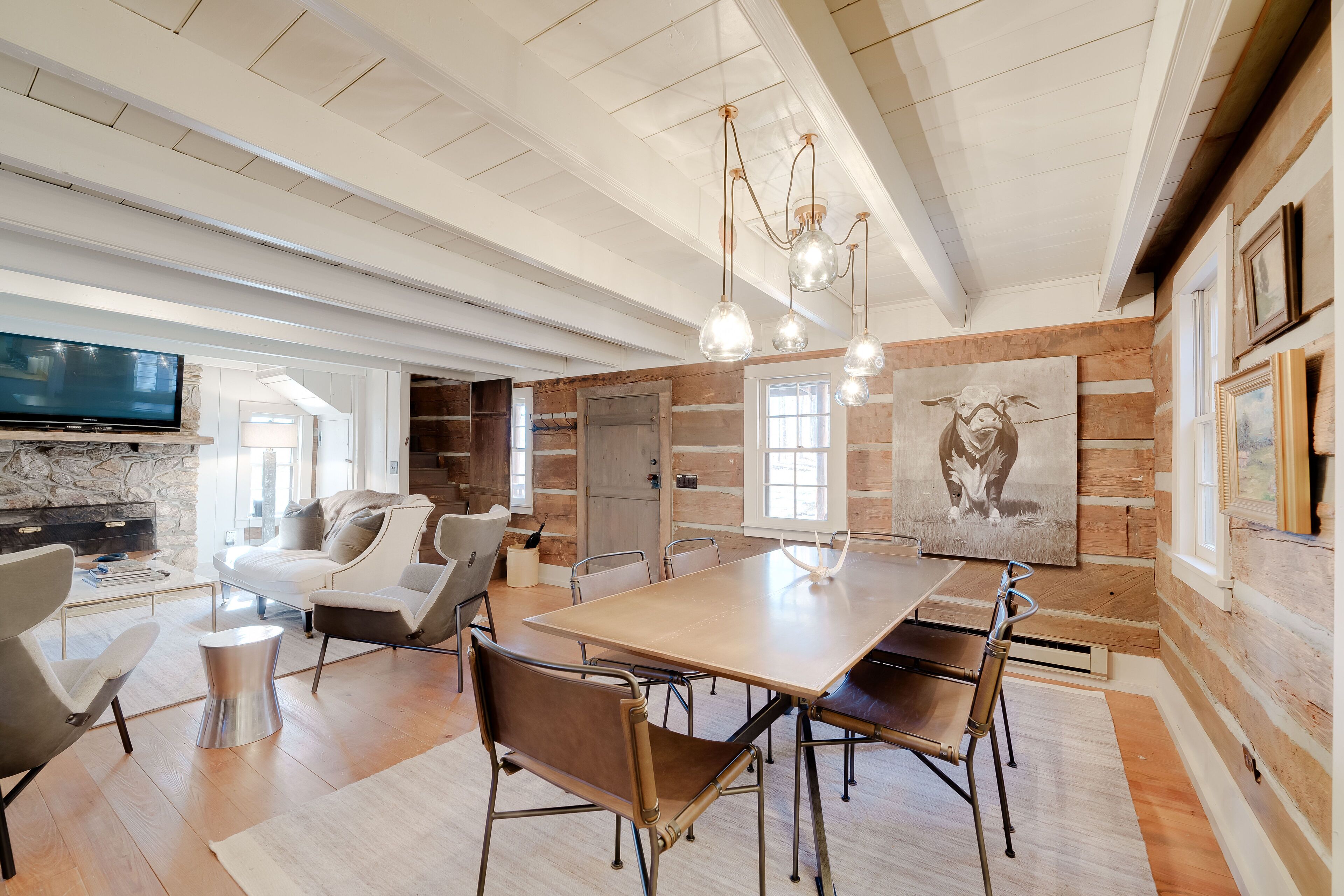 A spacious dining area with a large wooden table, modern chairs, and pendant lighting.