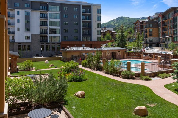 A modern hotel with multiple floors, a swimming pool, and a well-maintained garden. - Perfect for Summer Balcony with Pool View Heart of Village (Park City)