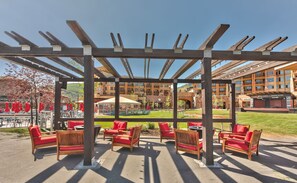 An outdoor patio with wooden pergola, red cushioned chairs, and tables. - Perfect for Summer Balcony with Pool View Heart of Village (Park City)