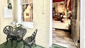 A room with a bed, a mirror, and a window with curtains. There is a table with chairs outside the room. - Fleur De Lis Mansion ,pool, near French Quarter & Superdome lic.Bnb  317134 (New Orleans)