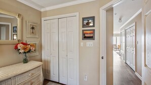 A hallway with a white door, a mirror, and a vase with flowers. - Beach Front Condo on the Strand, 101 Steps to the Beach  STR2021-00204 (Tybee Island)