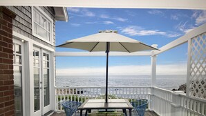 Un espace extérieur abrité, doté d’une table et de chaises, d’un grand parasol et offrant une vue sur l’océan.