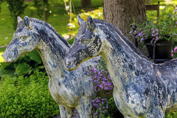 A garden statue of two horses with a potted plant beside them.