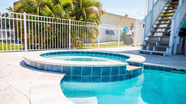 A swimming pool with a white fence and palm trees in the background. - A bit of Key West in New Port Richey: Bright Home w/ Pool & Boat Dock Access! (New Port Richey)
